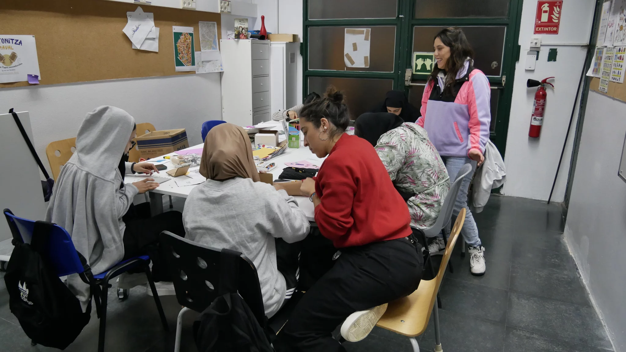 Noies al voltant d'una taula treballen en els seus projectes artístics.