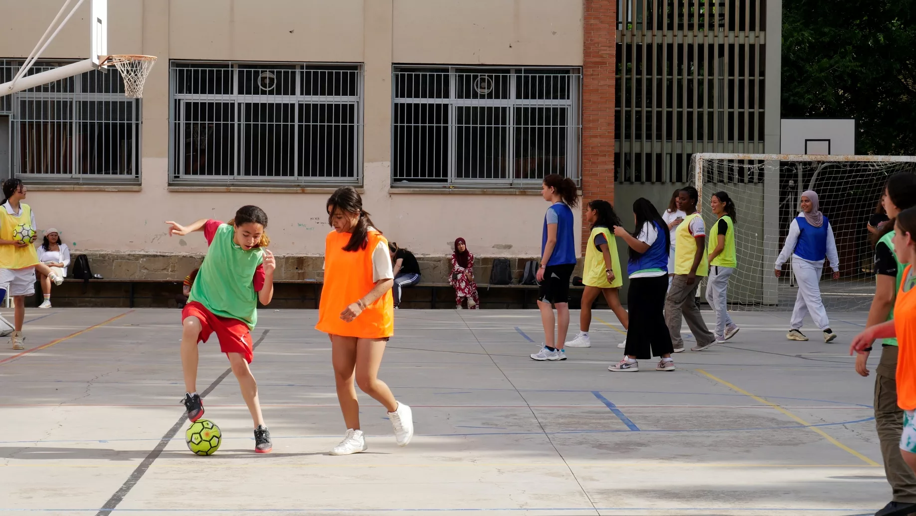 Noies juguen al futbol al pati d'una escola durant un torneig.