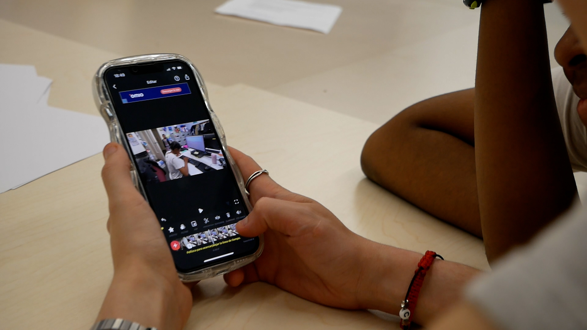 Detalls d'unes mans amb untelèfon mòbil, editant un vídeo.