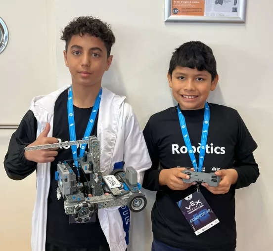 Dos nens somriuen a càmera, al campionat Vex Robotics.