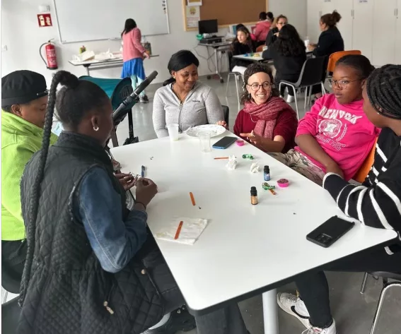 Mares, filles i educadora participen en una dinàmica sentades al voltant d'una taula.